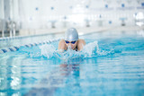 Young girl in goggles swimming breaststroke stroke style