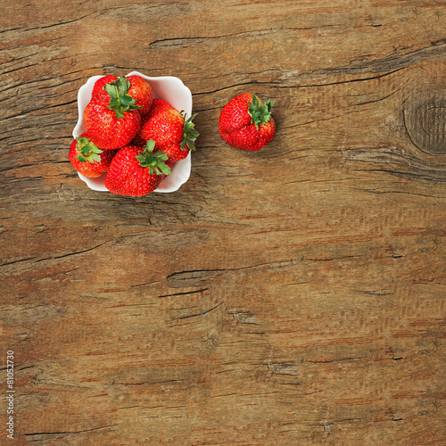 Fresh ripe strawberries in white bowl on wooden background.