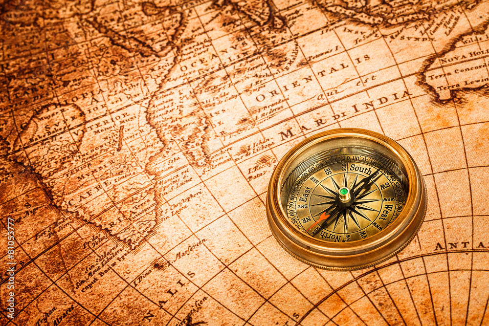 Vintage compass lies on an ancient world map.