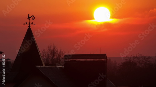 Magnificent sunset over the rooftops. wind indicator. red sun. photo