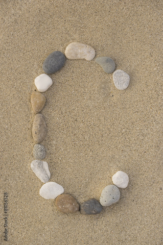 Buchstabe C aus Kieselsteinen im Sand