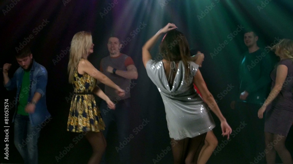 Girl the foreground dancing a silver dress. Happy young friends Girl the foreground dancing a silver dress. Happy young friends