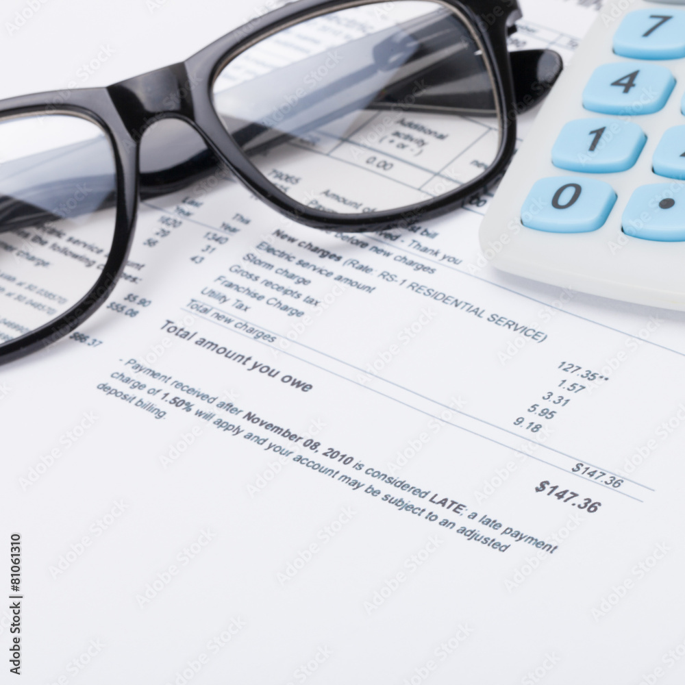Neat calculator with pen, glasses and utility bill Neat calculator with pen, glasses and utility bill