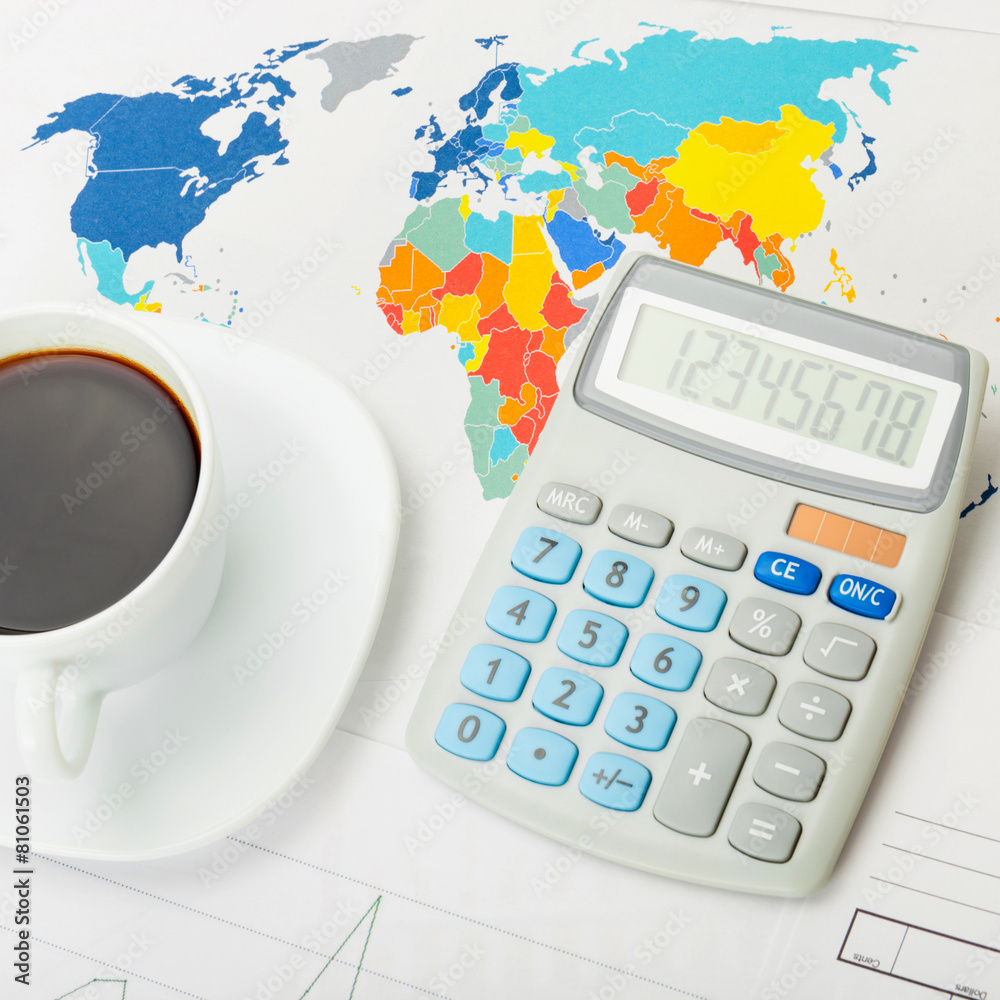 Coffee cup and calculator over world map - close up studio shot