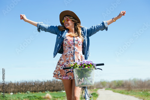 Beautiful young woman with a vintage bike in the field. photo
