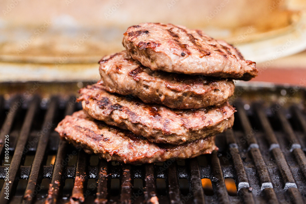 Pile of grilled ground beef patties on BBQ