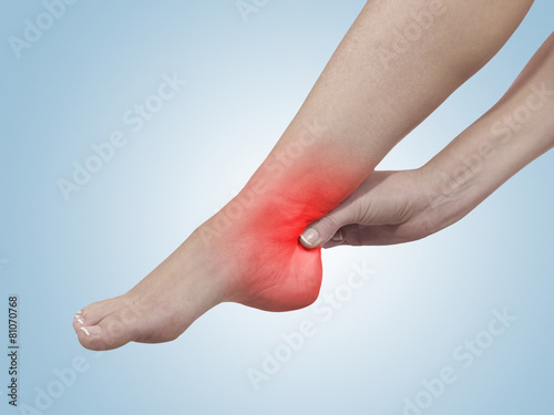 A young woman massaging her painful ankle