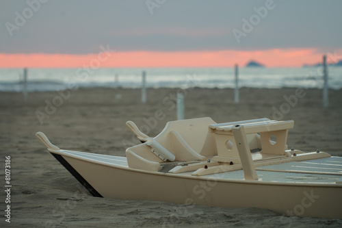 detail of wooden oar boat  half buried by the sand on the beach photo