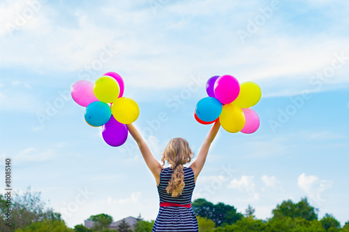 girl playing with colorful balloons against the blue sky