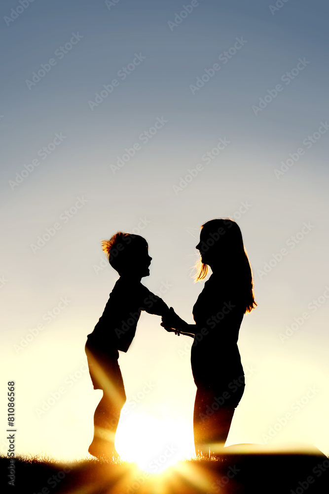 Silhouette of Mother and Young Child Holding Hands at Sunset