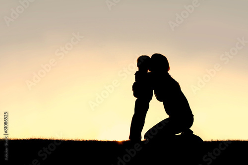 Silhouette of Young Mother Hugging Toddler Son at Sunset