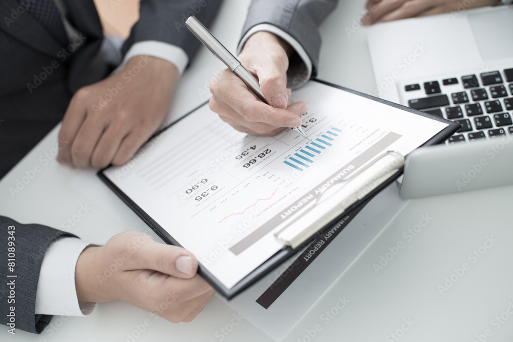 Two businessmen looking at report and having a discussion in off Two businessmen looking at report and having a discussion in off