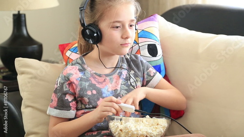 Little girl listening to music and eating popcorn