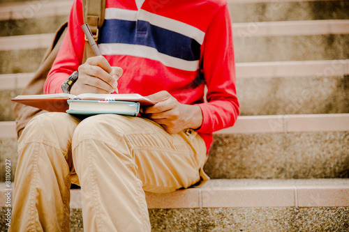 young college student reading book on stairs