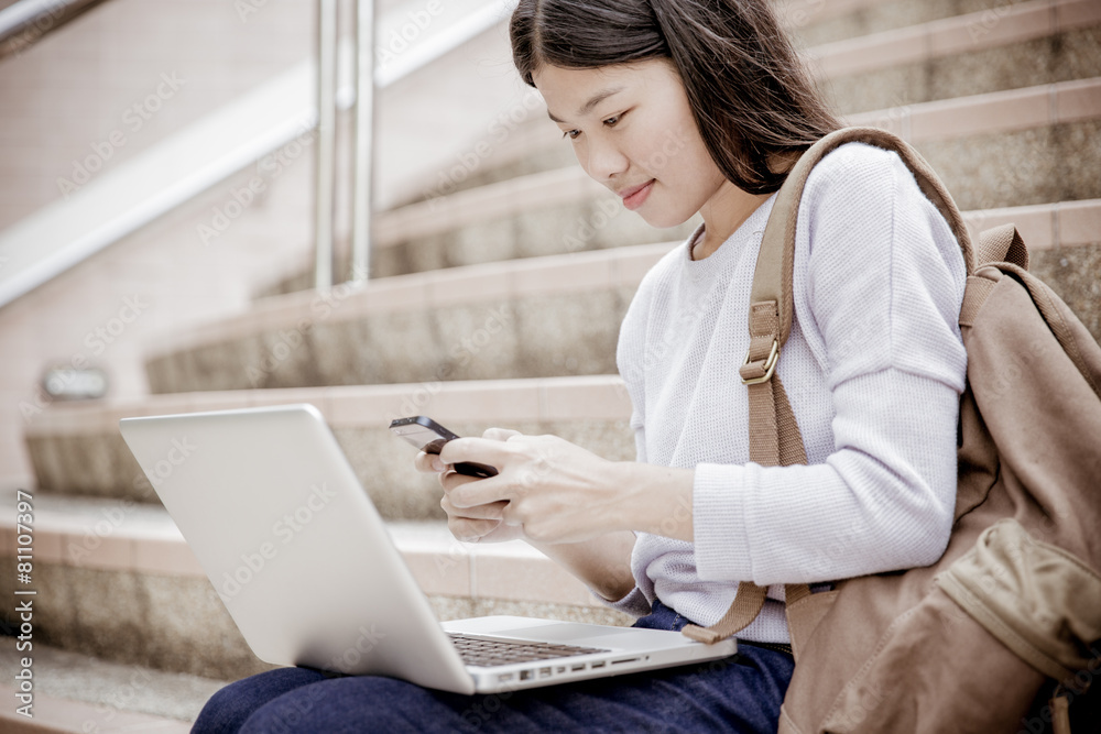 Young woman using laptop on steps outdoors