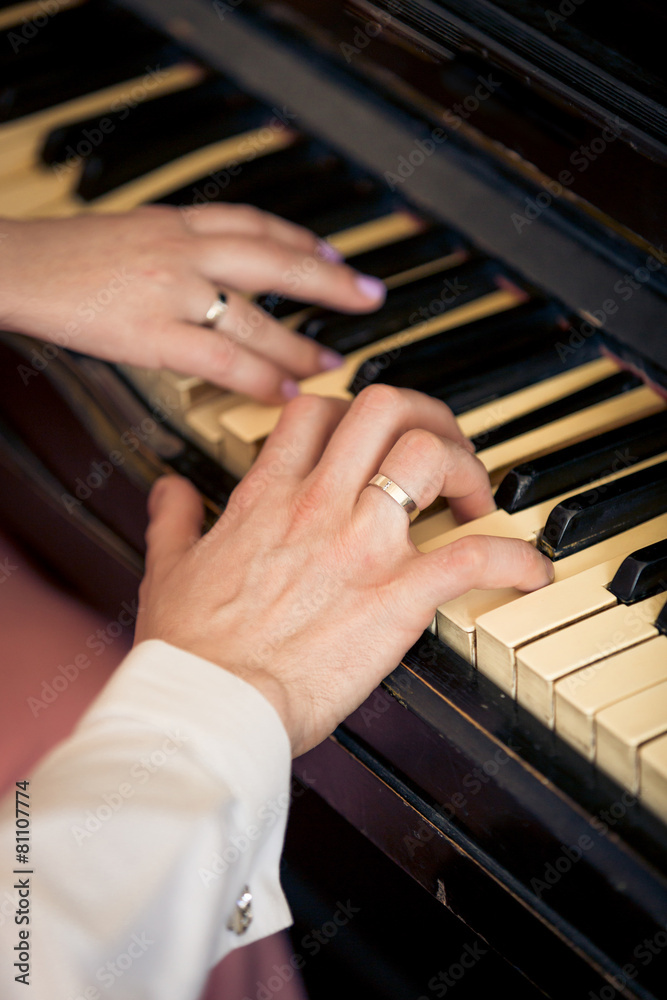 toned photo of newly married couple playing on piano