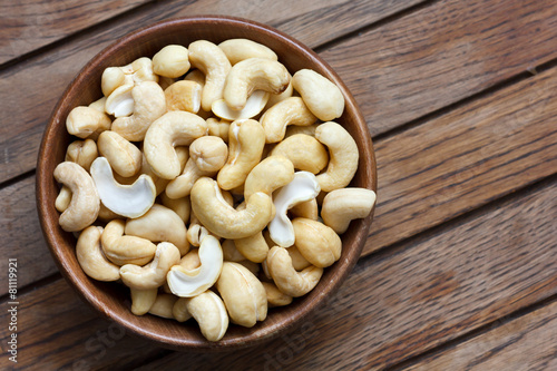 Wooden bowl of cashew nuts from above. On dark wood. photo