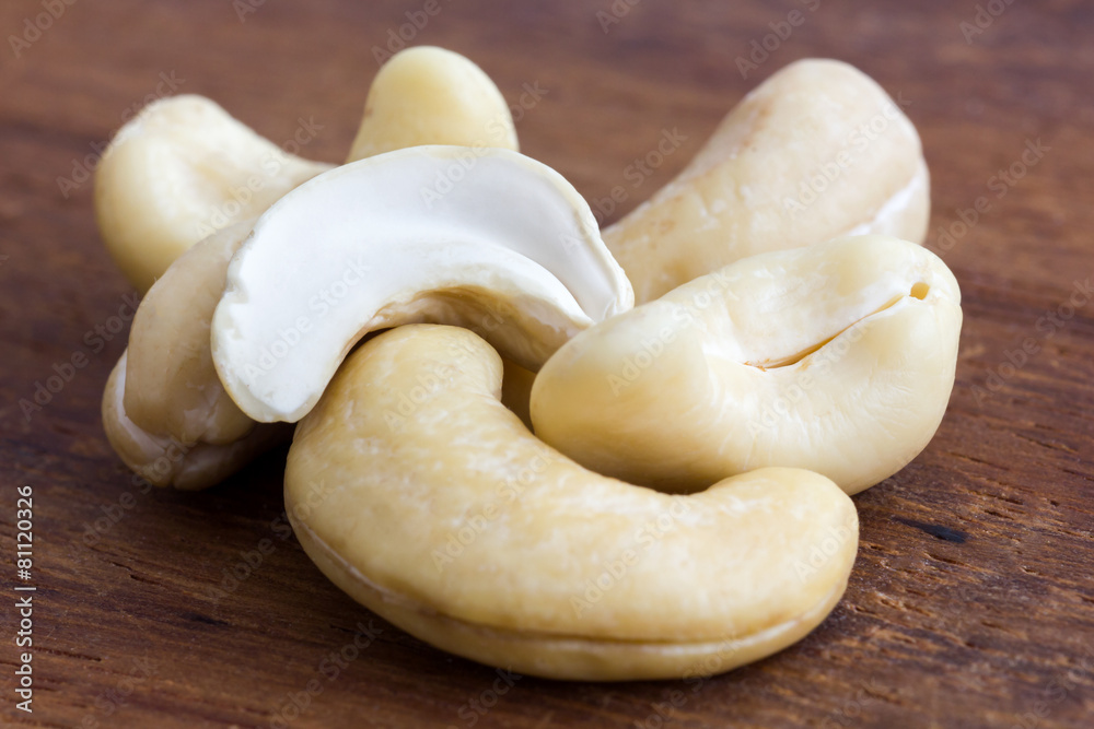 Detail of cashew nuts arranged on dark wood surface. Detail of cashew nuts arranged on dark wood surface.