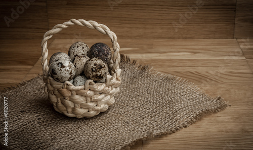 quail eggs in a basket on a wooden background