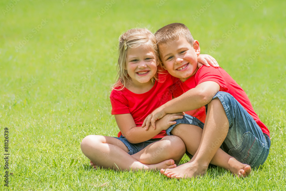 Fototapeta premium Brother and sister on lawn hugging.