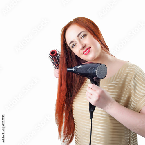 Redhead woman with long hair holding hair dryer and comb