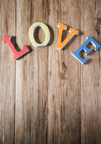 Wooden LOVE letters with vintage papers over wooden background a