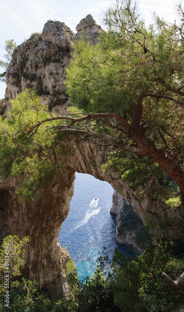 Boat passes under natural arch in Capri, Italy