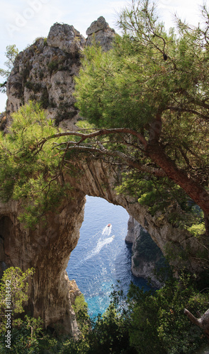Boat passes under natural arch in Capri, Italy