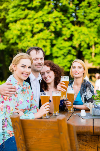 Freunde prosten mit Bier im Biergarten 