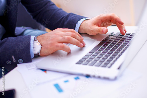 Businessman sitting at table with laptop and documents