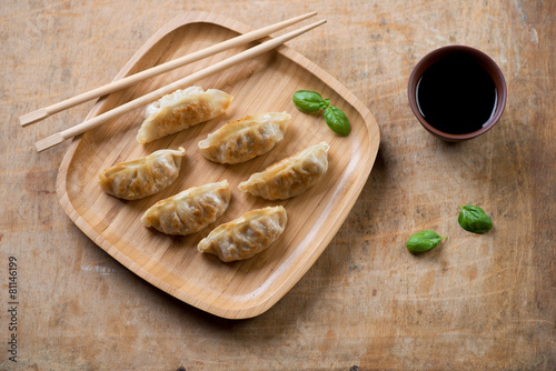 Pan fried gyoza dumplings with vegetables, rustic wooden surface