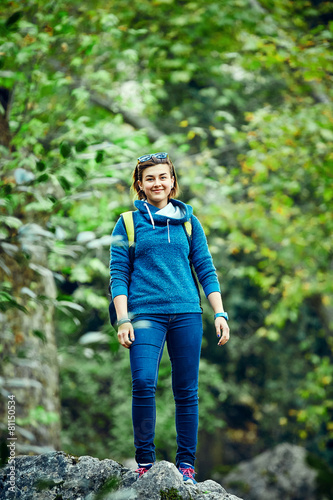 Woman hiker smiling standing outside in forest with backpack