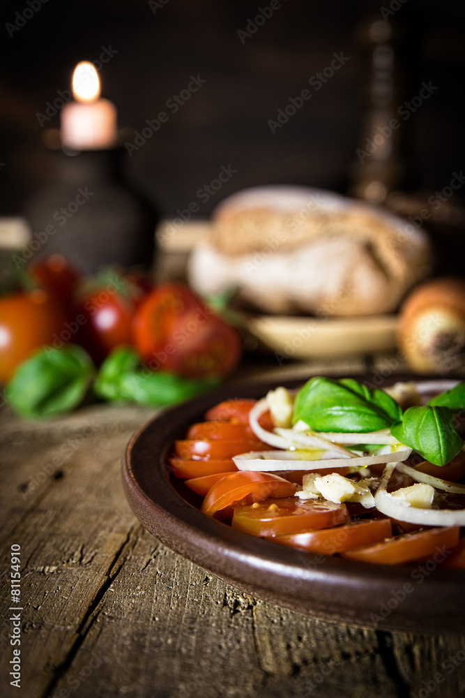 Tomatensalat mit Zwiebeln und Basilikum auf altem Holztisch mit