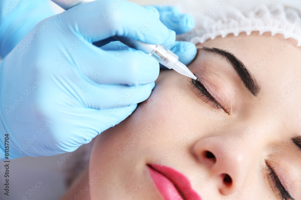 Cosmetologist applying permanent make up on eyes, close-up Cosmetologist applying permanent make up on eyes, close-up
