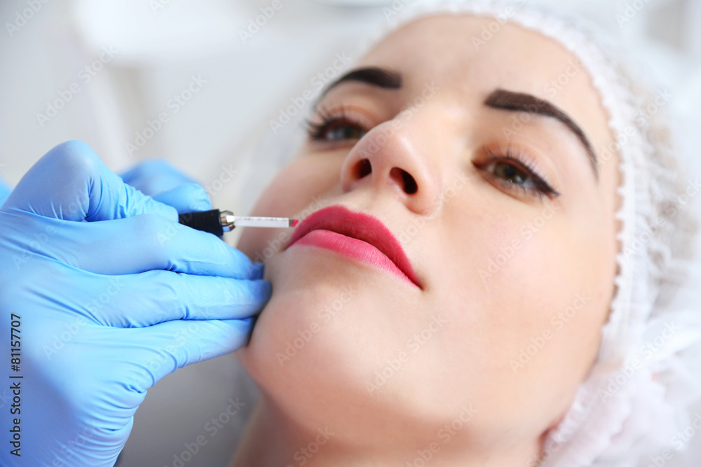 Cosmetologist applying permanent make up on lips Cosmetologist applying permanent make up on lips