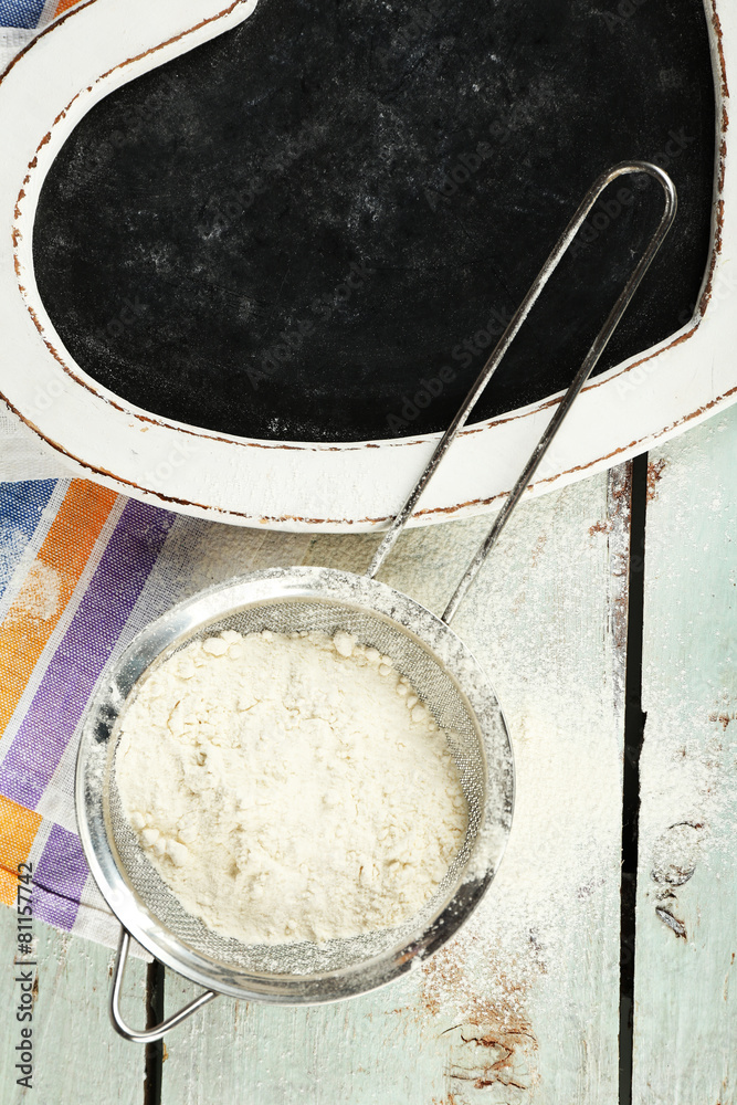 Fototapeta premium Sifting flour through sieve on wooden table, top view