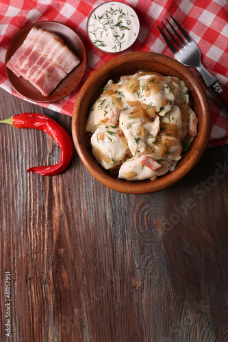 Fried dumplings with onion and bacon in frying pan,