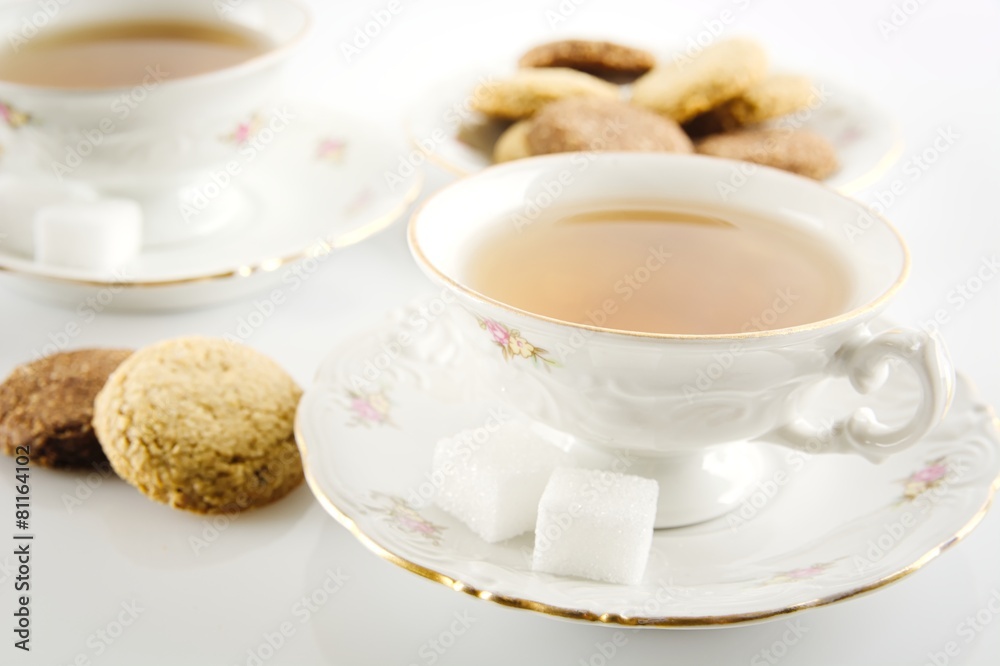 Old-style shot of cup of tea with cookies on white Old-style shot of cup of tea with cookies on white