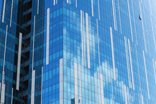 Glass facade of an urban building reflecting clouds