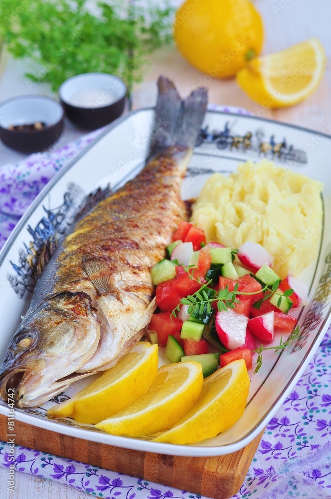 Fried fish served with mashed potato, lemon and vegetables salad Fried fish served with mashed potato, lemon and vegetables salad