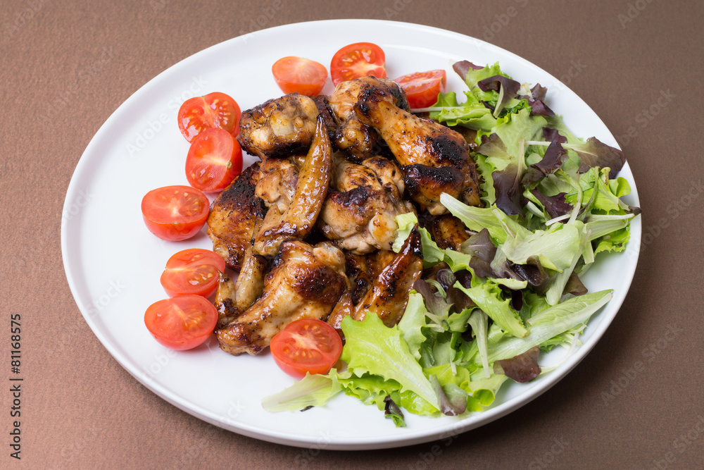 Chicken wings fried with honey decorated tomatoes and salad. Chicken wings fried with honey decorated tomatoes and salad.