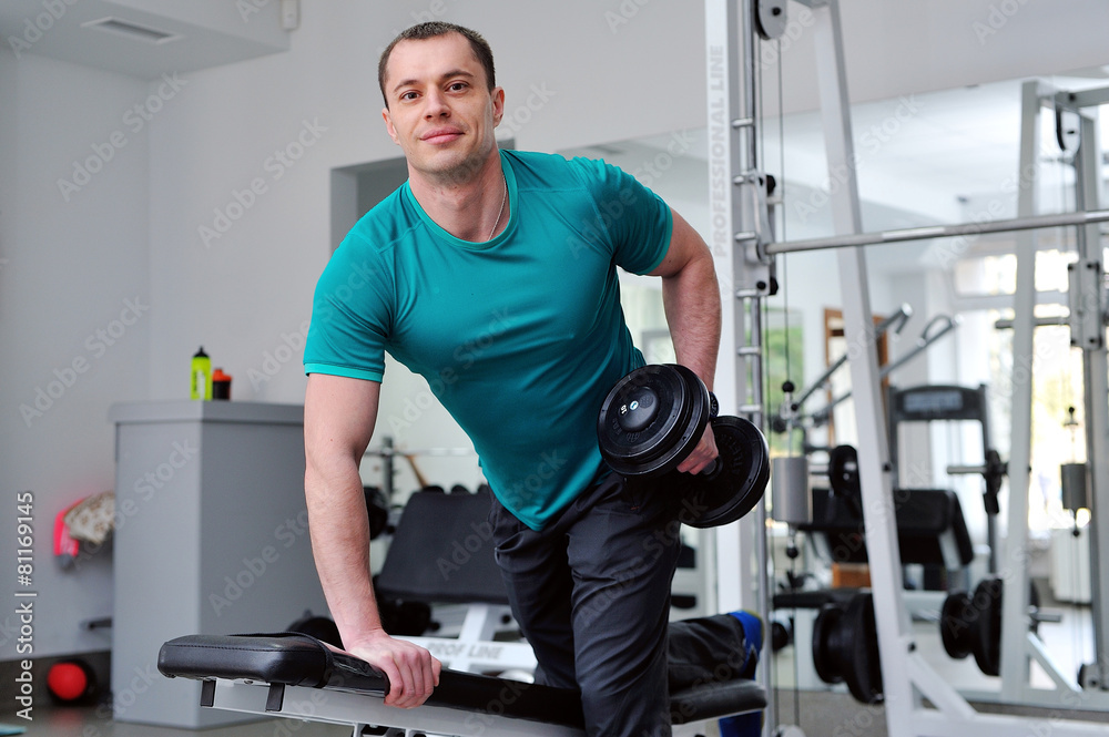 Image of fitness guy in gym exercising with dumbbells Image of fitness guy in gym exercising with dumbbells