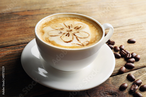 Cup of coffee latte art with grains on wooden background