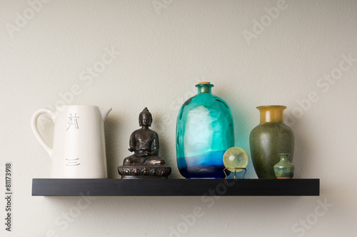 Wall shelf featuring pottery and a buddha