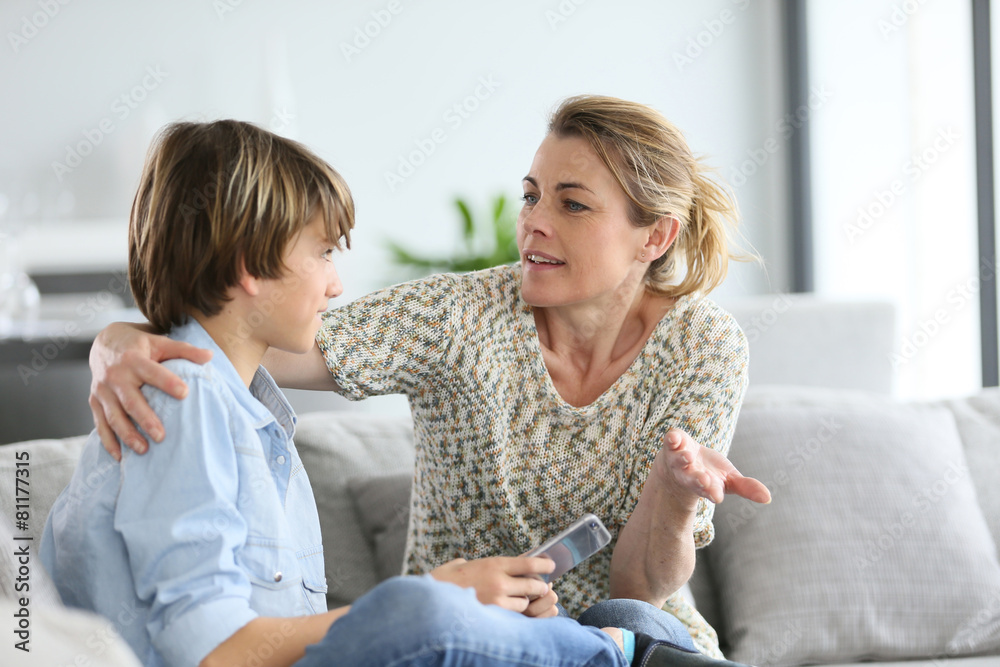 Mother giving warning to young boy using smartphone - obrazy, fototapety, plakaty 