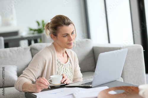 Middle-aged woman working from home on laptop © goodluz