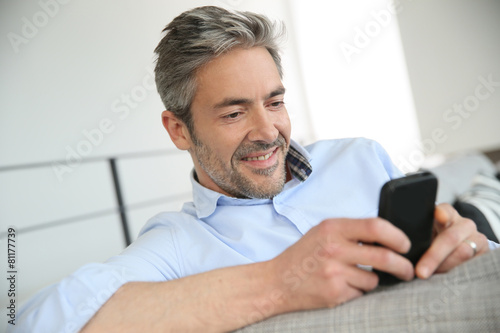 Mature man sending message with smartphone
