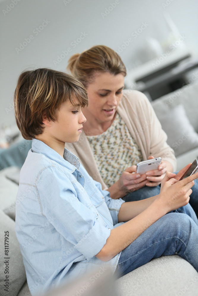Mother and teenage boy playing with smartphone Mother and teenage boy playing with smartphone