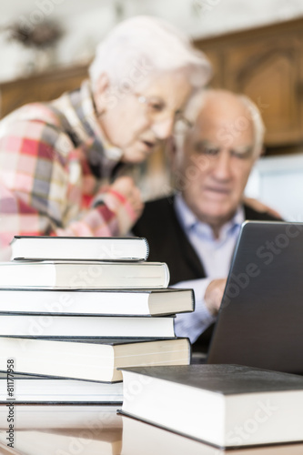Senior couple working with Laptop and books at home © photopitu