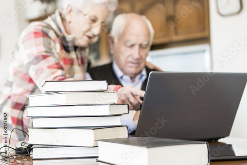 Senior couple working with Laptop and books at home © photopitu